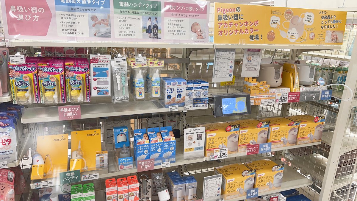 Nasal aspirator display at a Japanese baby shop, showing shelves labelled by type — electric tabletop, electric handy, and manual or mouth-suction